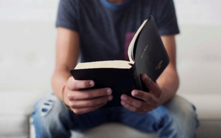 man in jeans reading bible