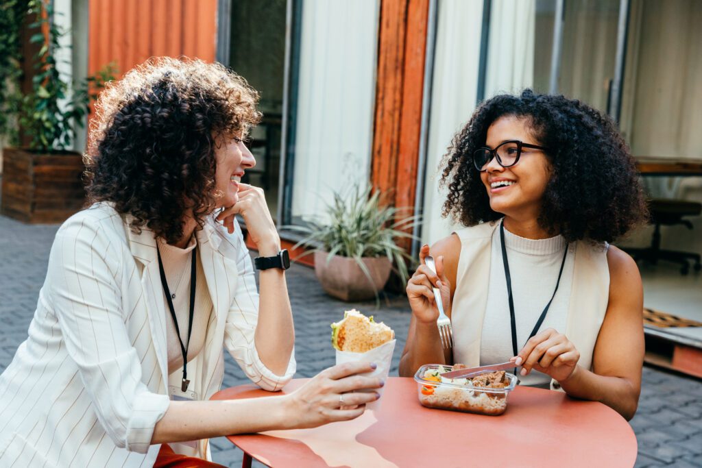 two women sharing a lunch at an outdoor circular table.