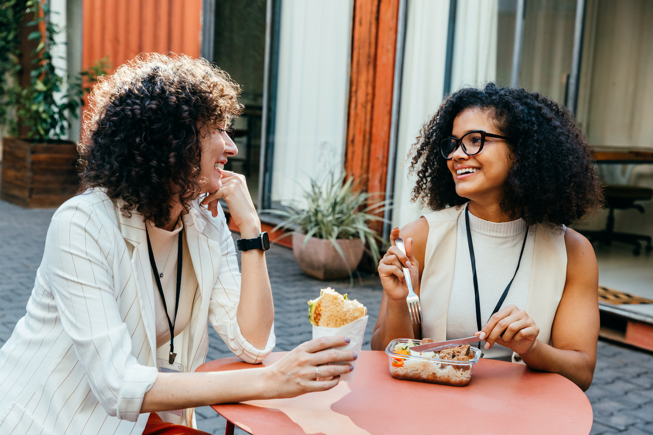 two women sharing a lunch at an outdoor circular table.