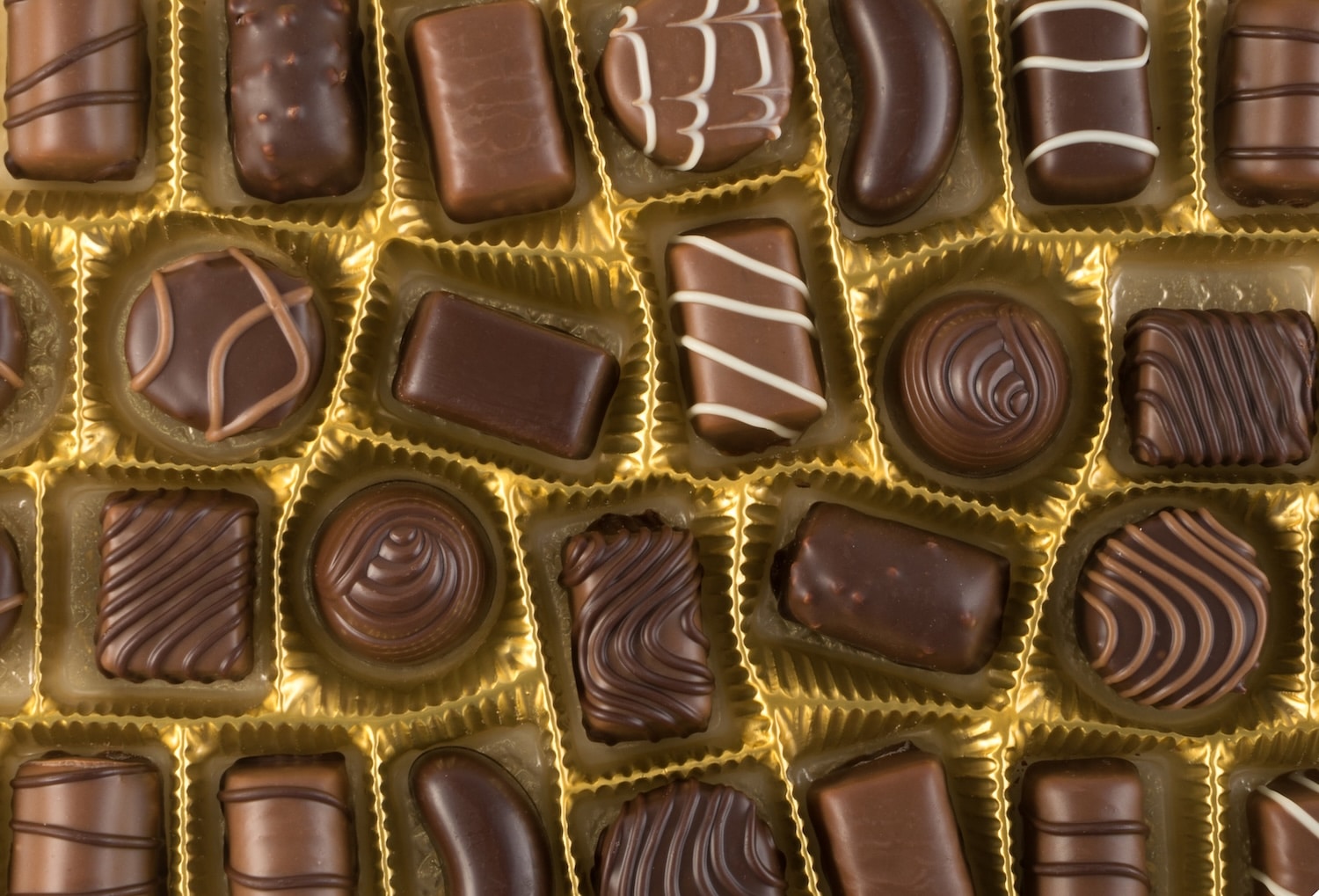 Assorted chocolates in a gold display tray with individual compartments.